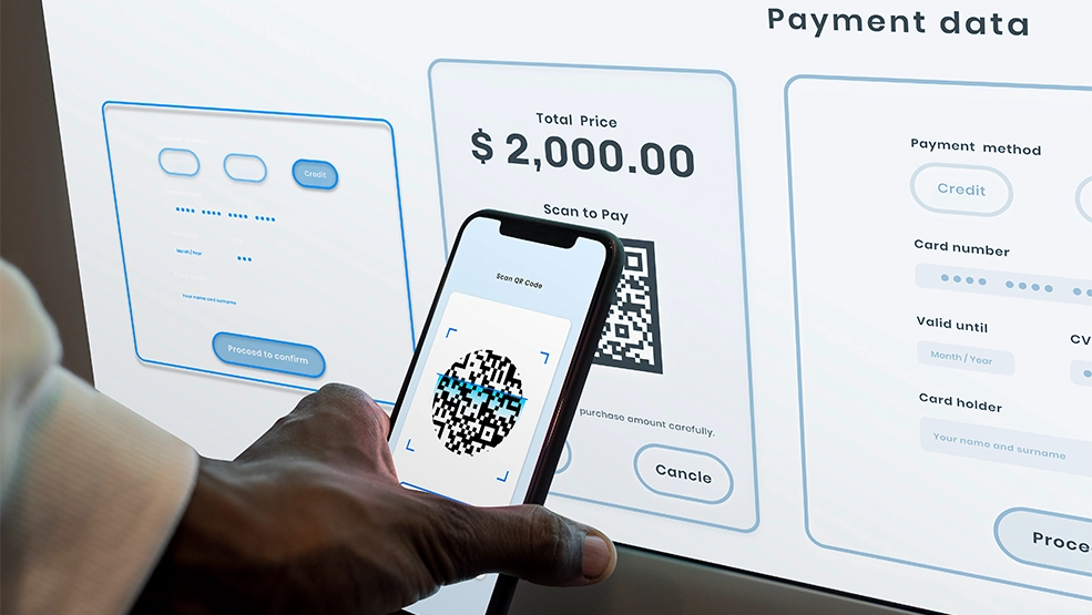 Smartphone scanning QR code on payment screen displaying $2,000.00 total price with credit card entry form