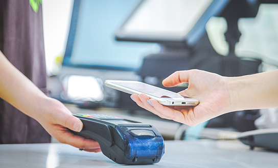Customer paying with smartphone using NFC contactless technology at a point-of-sale terminal