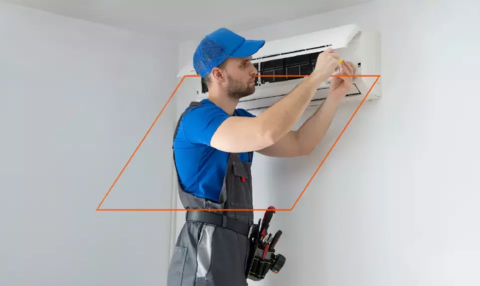 HVAC technician in blue uniform servicing a wall-mounted mini-split air conditioning unit