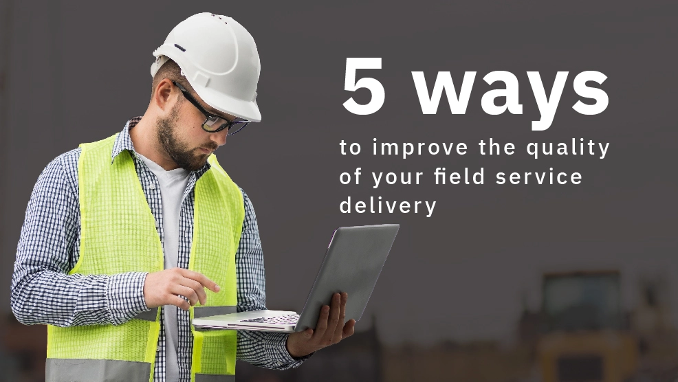 Field service technician in hard hat and safety vest using laptop on job site