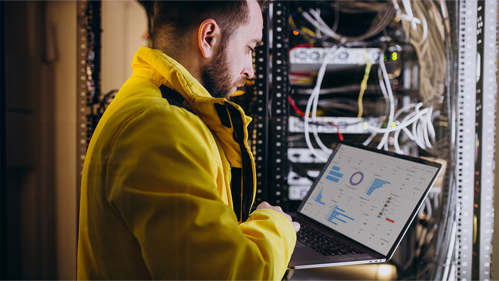 IT technician analyzing performance dashboard on laptop in server room