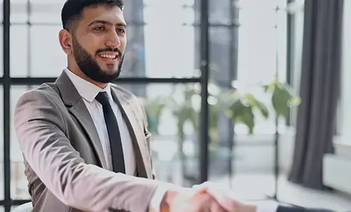 Smiling businessman in gray suit shaking hands in a modern office setting