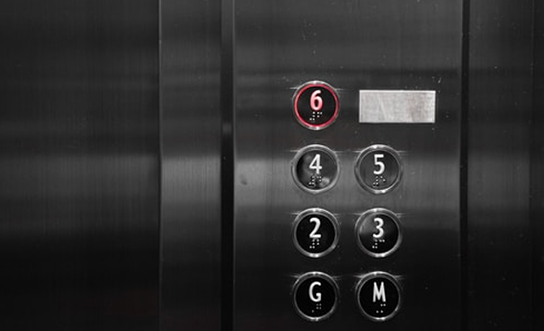 Elevator control panel with floor buttons G, M, 2, 3, 4, 5, and 6, with floor 6 illuminated in red