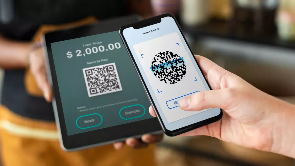 Customer scanning QR code on smartphone to complete $2,000 payment at point of sale terminal