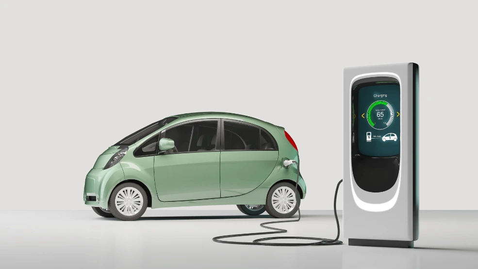 Electric vehicle plugged into charging station displaying 65% battery level on digital screen