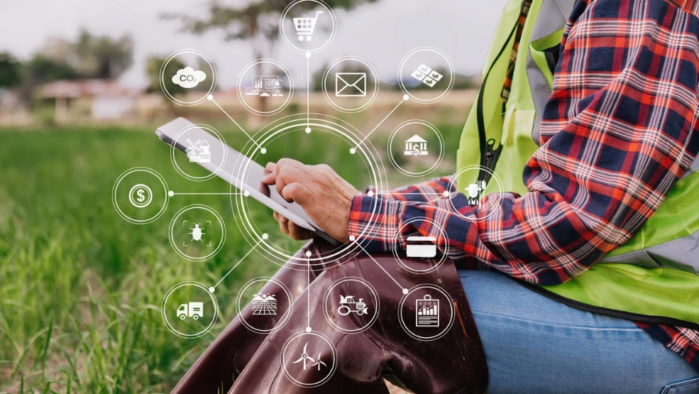Farmer using tablet in field with digital icons showing smart agriculture management tools and analytics