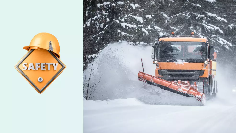 Orange snowplow truck clearing a snow-covered road lined with pine trees during a winter storm
