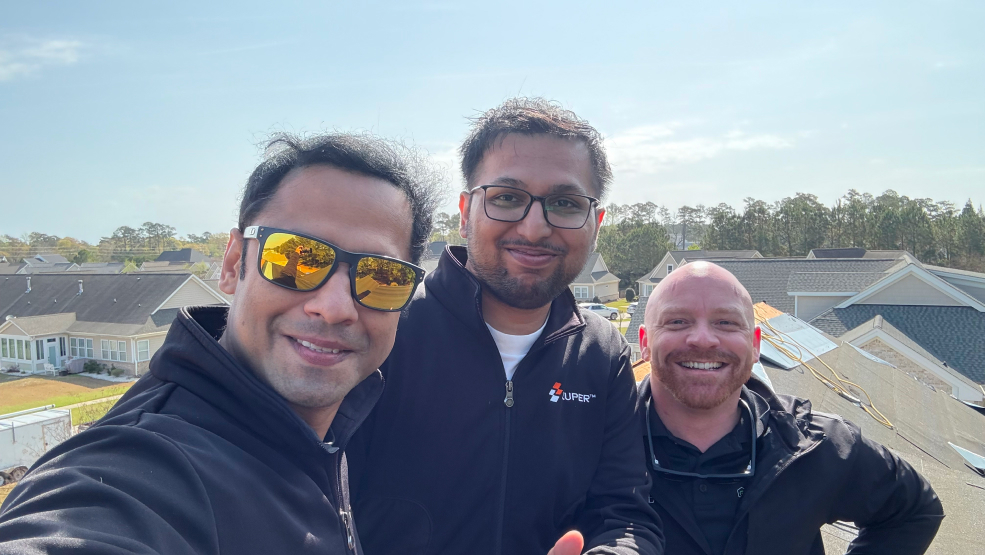 Zuper team members taking a selfie on a residential rooftop during a job site visit