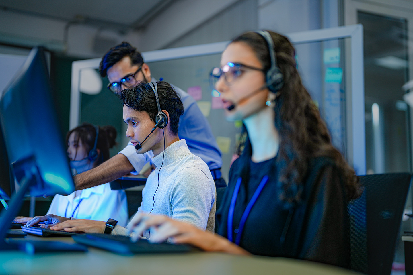 Call center team with headsets working at computer workstations in a modern office environment
